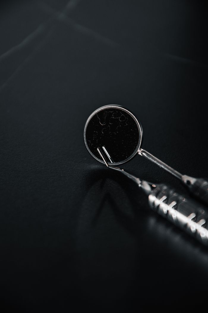 Detailed close-up of dental tools with a reflective surface on a black background.